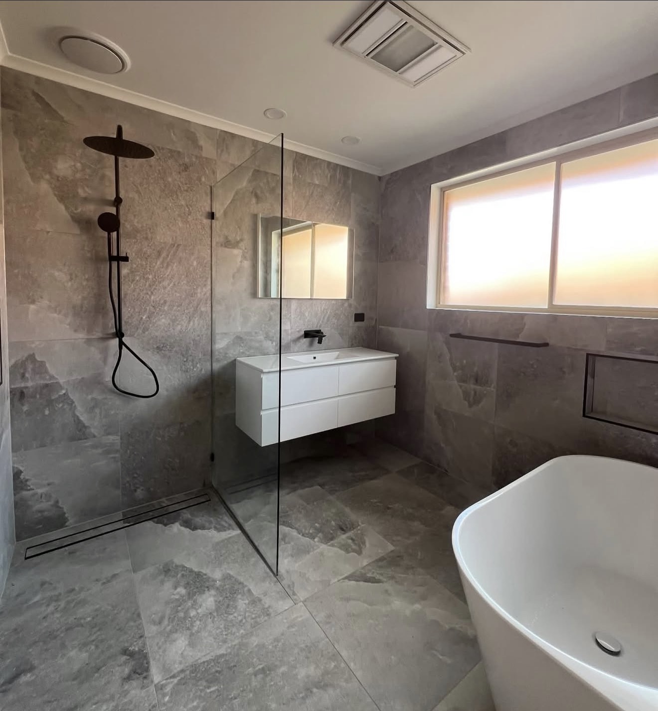 Bathroom with shower, freestanding bath and stone tiles