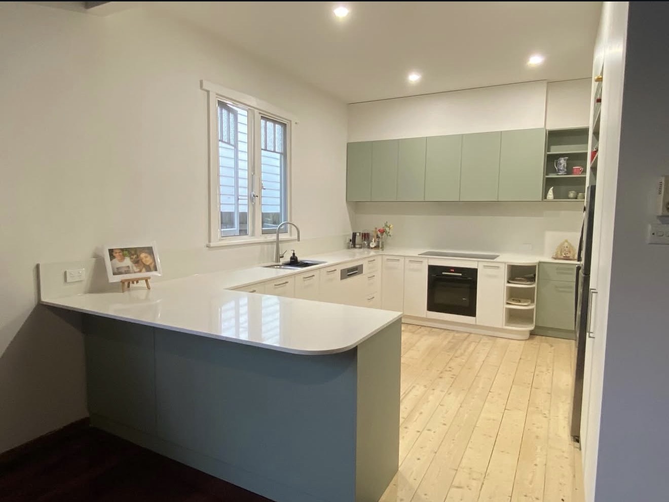 Kitchen with sage cabinetry and stone benchtops