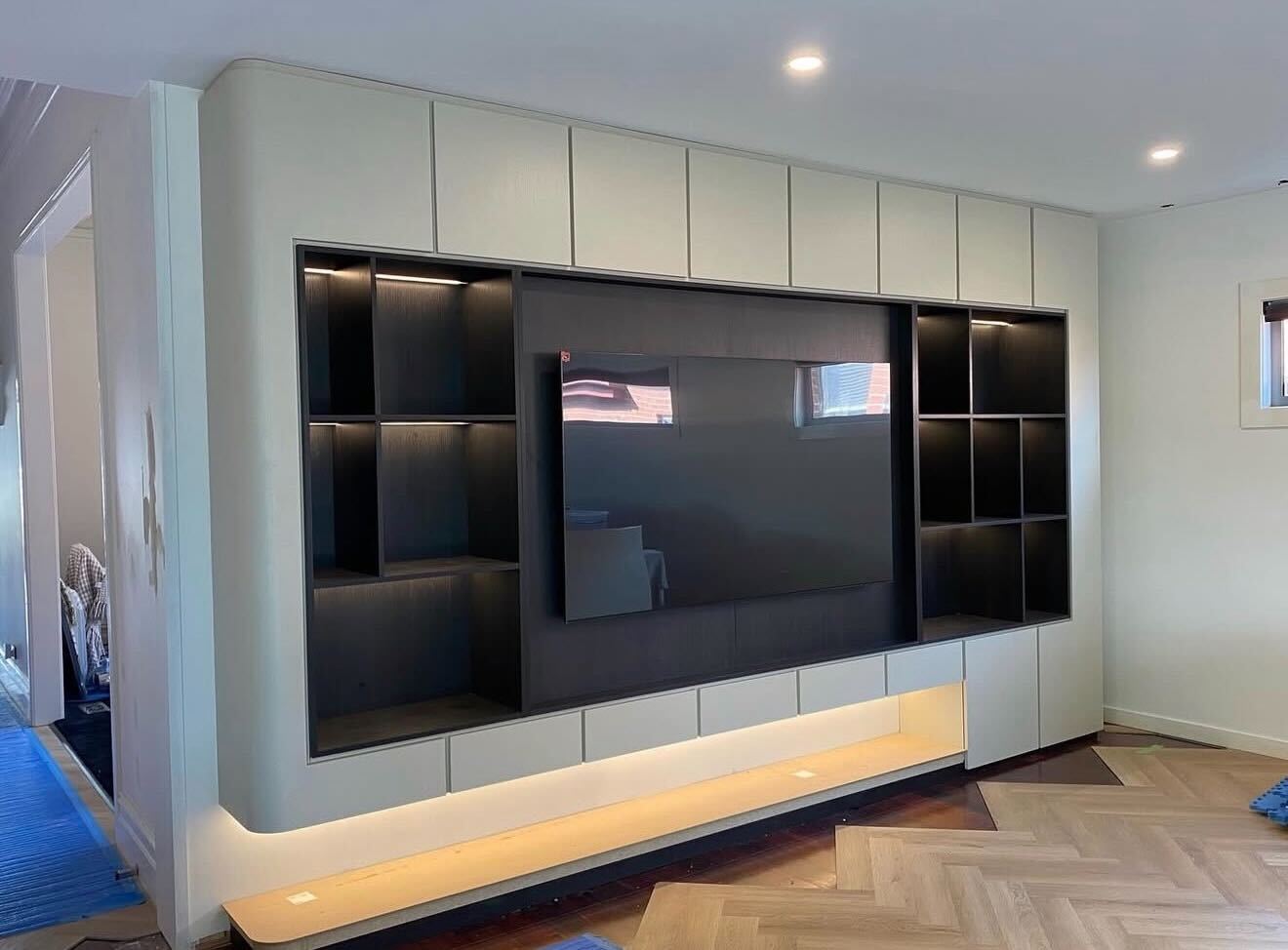 Custom built-in TV unit with integrated shelving and LED lighting