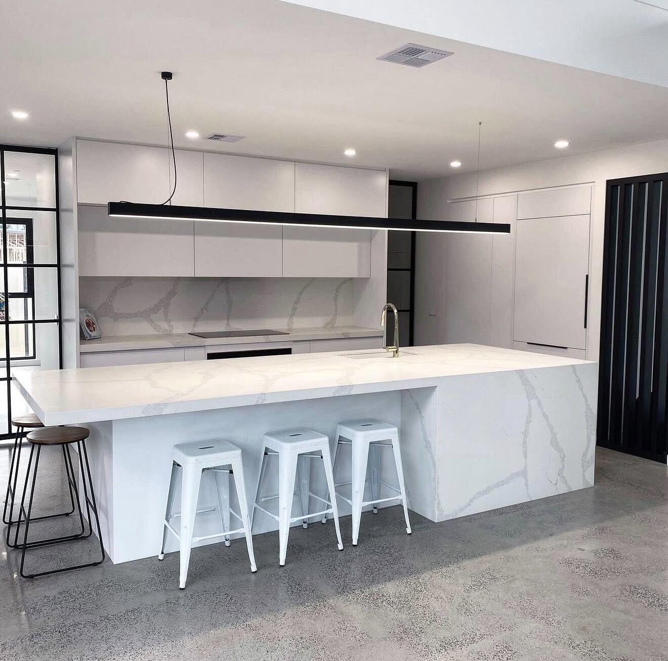 Modern white kitchen with stone waterfall island and pendant lighting